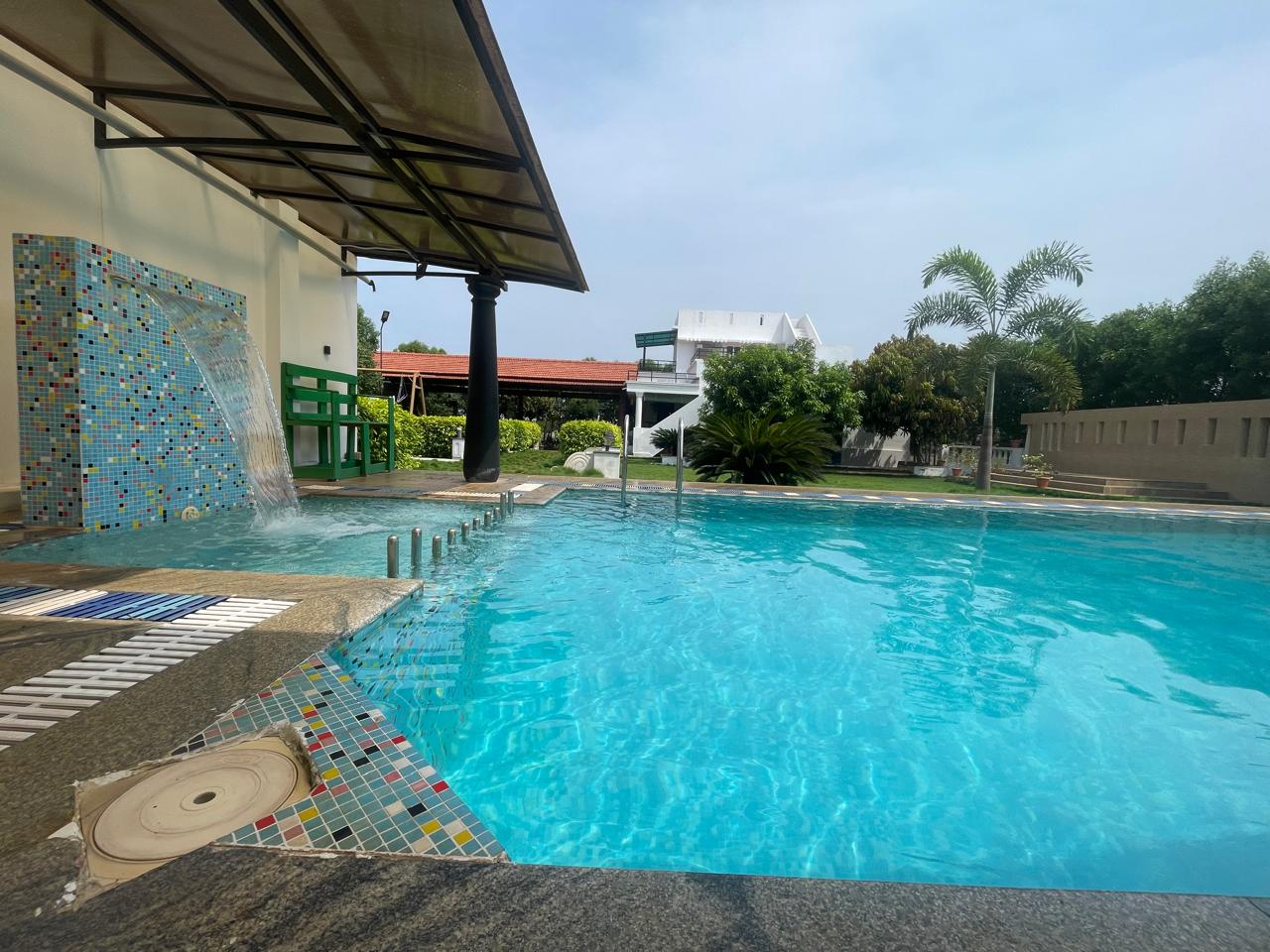 Sunlit swimming pool at Nellai Farm House during daytime